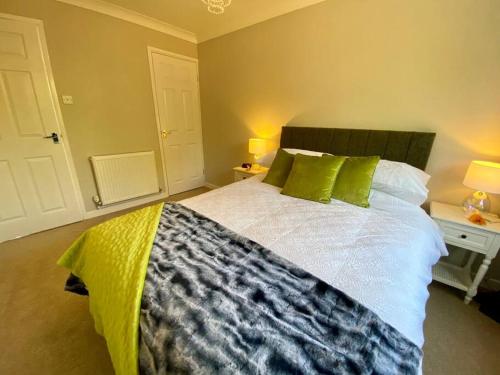 a bedroom with a large bed with green pillows at Cosy Bungalow Near Open Countryside in Felixstowe