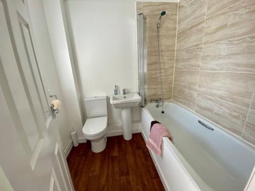 a bathroom with a sink and a toilet and a bath tub at Cosy Bungalow Near Open Countryside in Felixstowe