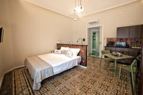 a bedroom with a bed and a table and a kitchen at Cave Bianche Apartments in Favignana