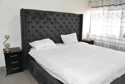 a bedroom with a large bed with a black headboard at Specious Old Zamtel flats in Lusaka