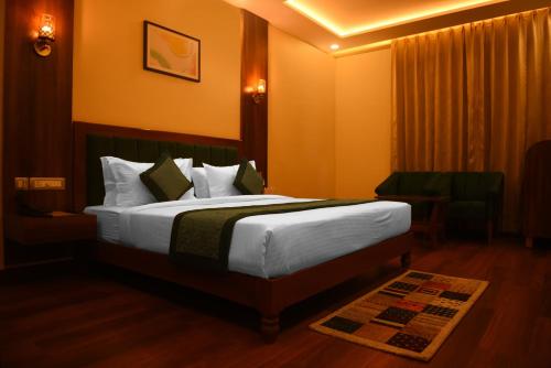 a hotel room with a large bed and a chair at The Abhyudyam Ganga in Haridwār