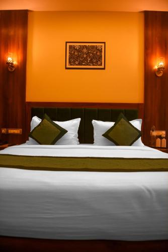 a bedroom with a large white bed with green pillows at The Abhyudyam Ganga in Haridwār