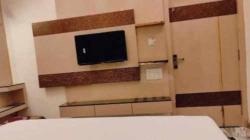 um quarto com uma televisão na parede e uma cama em SHRADDHA HOTEL em Alīgarh