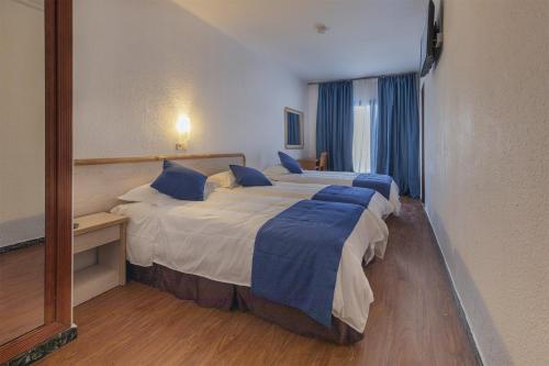 Habitación de hotel con 2 camas y almohadas azules en Hotel Vila Calella, en Calella