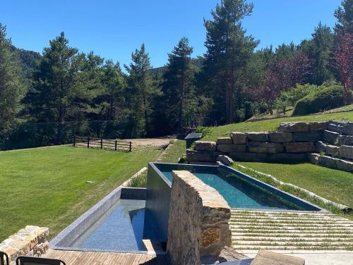 een zwembad in een tuin met een stenen muur bij El Refugi de la Torre Espinalbet in Castellar del Riu