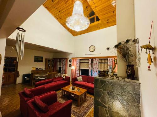a living room with red couches and a wooden ceiling at Aashirwad Homestay Kullu in Kulu