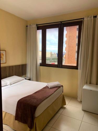 a bedroom with a bed and a large window at Ocean Praia Hotel in Fortaleza