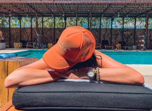Kobieta w pomarańczowym kapeluszu siedząca obok basenu w obiekcie Hotel Saint George w mieście Marfa
