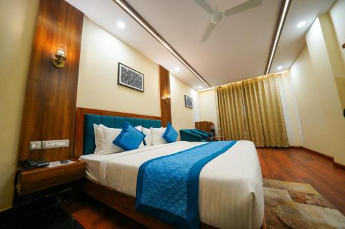 a hotel room with a large bed with blue accents at The Abhyudyam Ganga in Haridwār