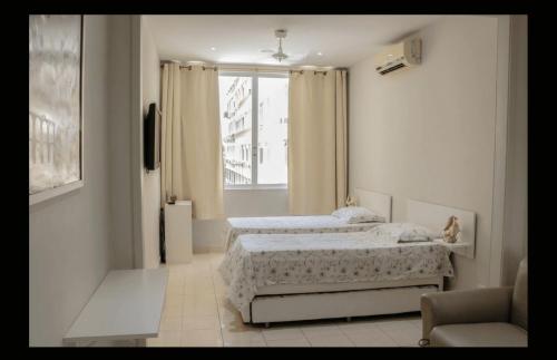 1 dormitorio con 2 camas y ventana en Copacabana Vista Mar Studio, en Río de Janeiro