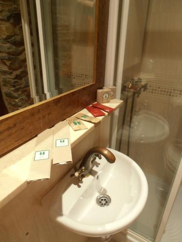 a bathroom with a sink and a mirror and a toilet at Hostal Virgen de la Encina in Ponferrada