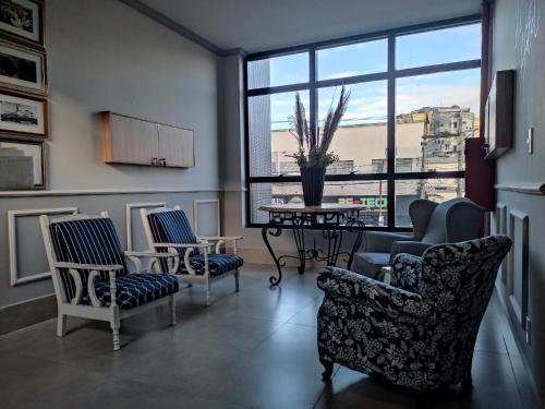 a living room with chairs and a table and a large window at AVENIDA HOTEL DE RESENDE in Resende