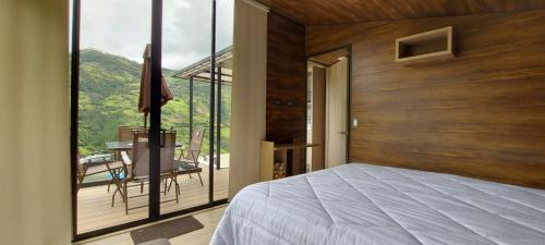 1 dormitorio con cama y vistas a un balcón en Glamping Mirador del Guavio, en Ubalá