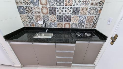 a small kitchen with a sink and a tile wall at Apartamento kit Praia Grande na Guilhermina Frente Mar in Praia Grande