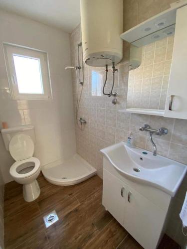 a white bathroom with a toilet and a sink at Apartman MARA in Šestanovac