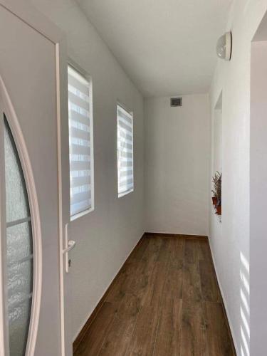 an empty room with a door and two windows at Apartman MARA in Šestanovac