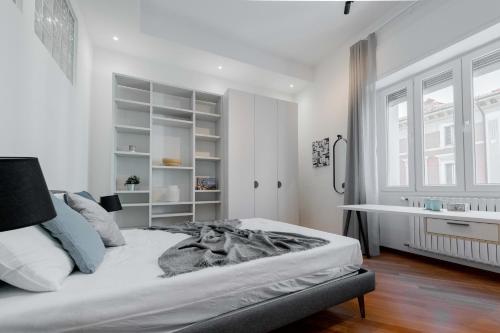 a white bedroom with a bed and a desk at Realkasa Amendola Apartment in Bologna