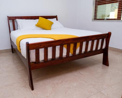 una cama de madera con una manta amarilla. en Gukurume- Gaborone en Gaborone