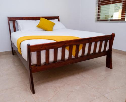 a wooden bed with a yellow blanket on it at Gukurume- Gaborone in Gaborone