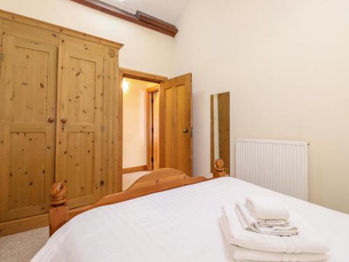 1 dormitorio con cama blanca y armarios de madera en The Hayloft en Keswick