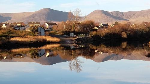 a reflection of houses in the water with mountains in the background at Kenmare Eco Lodge in Kenmare