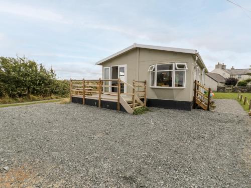 a small house with a fence and a gravel driveway at Porthwen Lodge in Amlwch