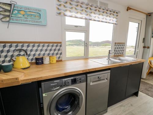 a kitchen with a washing machine and a sink at Porthwen Lodge in Amlwch