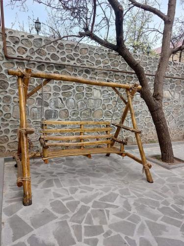 a wooden bench sitting next to a stone wall at Zangezur Hotel in Goris