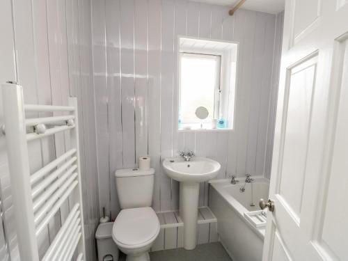 Baño blanco con aseo y lavamanos en 11 Bro Celyn, en Holyhead