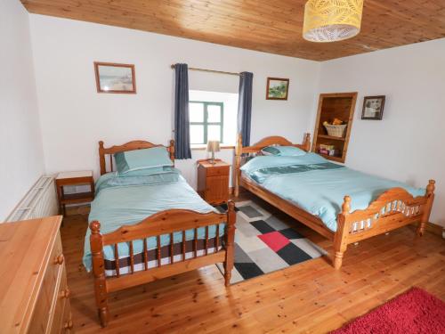 a bedroom with two beds and a wooden floor at Toms Cottage in Westport