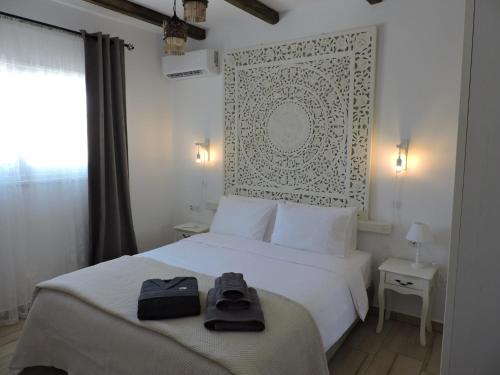 a bedroom with a white bed with two bags on it at Onar Luxury Villa - Adults Only in Lachania