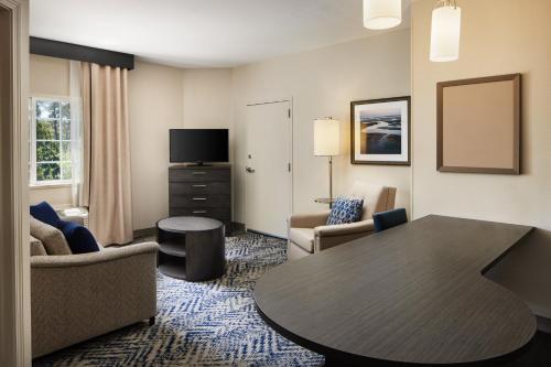 a living room with a table in a hotel room at Candlewood Suites Charleston-Northwoods by IHG in Charleston