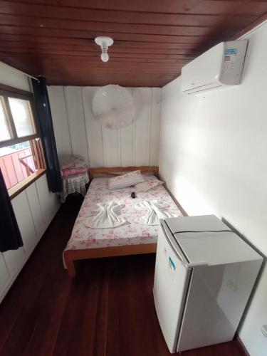una piccola stanza con un letto e un frigorifero di Pousada Trilha do Farol a Ilha do Mel