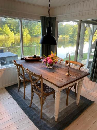 a dining room table with a vase of flowers on it at Hyggelig sommerhus. med udsigt, til vand fra senge in Veksø