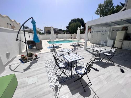 patio ze stołami i krzesłami przy basenie w obiekcie B&B Alto Salento - Pool and Sun w mieście Pulsano