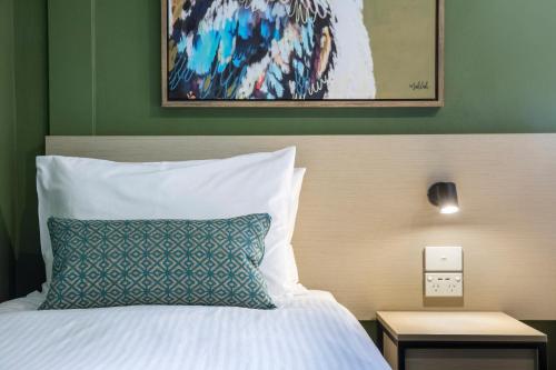 a bedroom with a bed with a blue pillow at Nightcap at Pritchards Hotel in Mount Pritchard