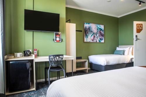 a hotel room with two beds and a desk with a chair at Nightcap at Pritchards Hotel in Mount Pritchard