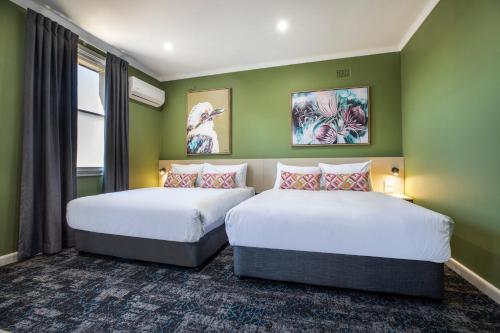 2 Betten in einem Zimmer mit grünen Wänden in der Unterkunft Nightcap at Pritchards Hotel in Mount Pritchard