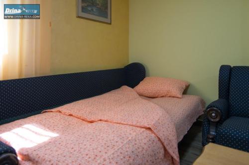 een slaapkamer met een bed met roze lakens en een stoel bij Apartman Raj Macevine in Bajina Bašta