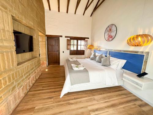 a bedroom with a large white bed and a tv at Hotel Boutique El Carmel in Villa de Leyva