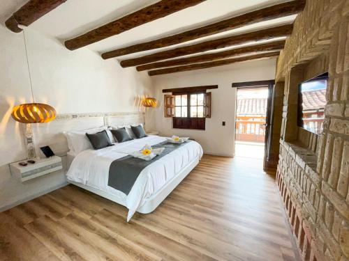 a bedroom with a large white bed and wooden floors at Hotel Boutique El Carmel in Villa de Leyva