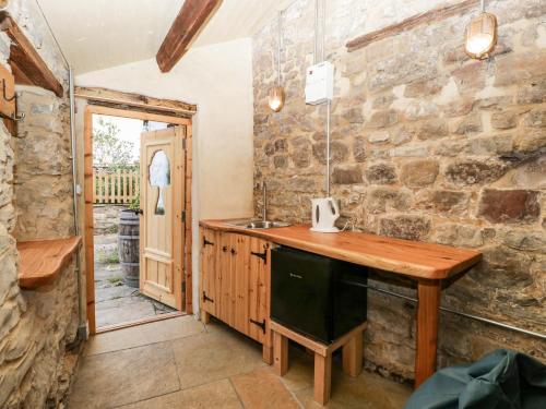 a kitchen with a wooden counter and a stone wall at Tinmans Cottage in Lydbrook