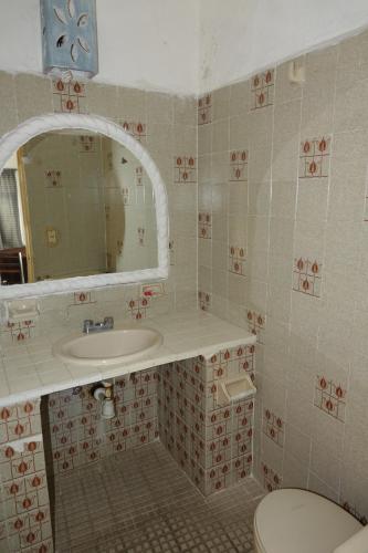 a bathroom with a sink and a mirror and a toilet at Suites La Audiencia in Manzanillo