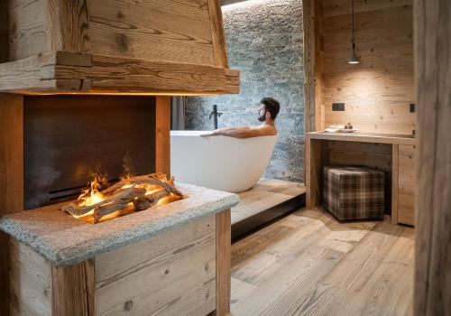 a man in a bath tub in a bathroom with a fireplace at Sci Sport rooms & suites in Bormio