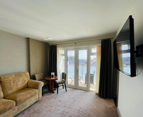 a living room with a couch and a tv and a table at La Barbarie Hotel in St Martin Guernsey