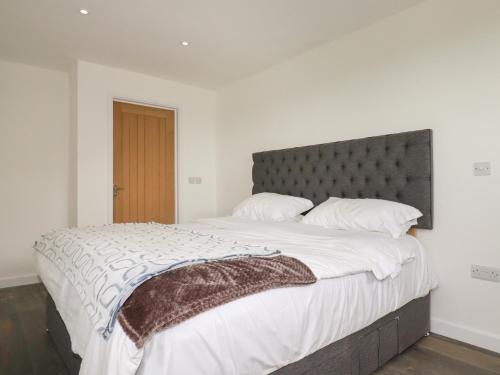 a bedroom with a large bed with a gray headboard at Atlantic Apartment in Bude