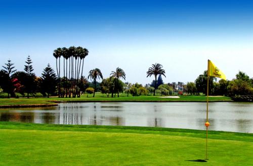 a golf course with a pond and a yellow flag at AIRE DE SOTOGRANDE in Sotogrande
