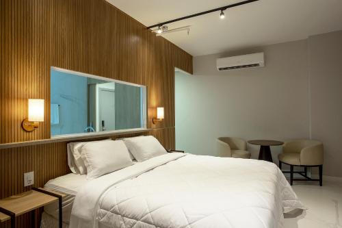 a bedroom with a large white bed and a mirror at Slaviero Rondonópolis Centro in Rondonópolis