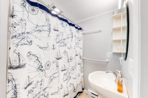 a bathroom with a shower curtain with a sink at Beach Rose Guest Studio in Nauset Heights