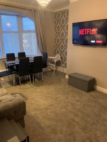 a living room with a table and a television on the wall at Pleasure Beach View in Blackpool